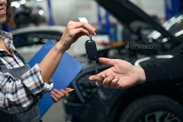 Woman auto repairman hands over car keys to client
