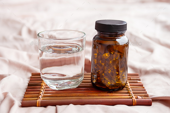 Omega 3 oil capsules and water glass on tray. Fatty acids nutritional