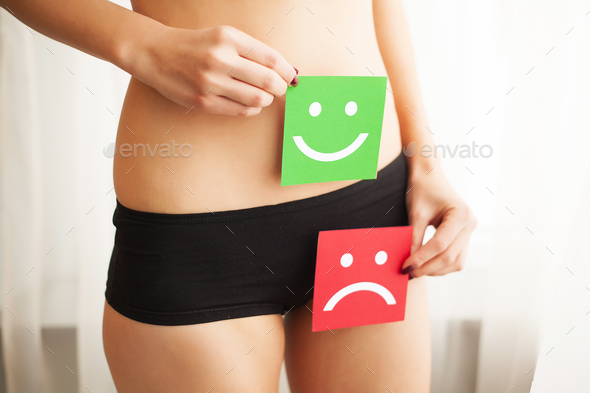  Wman With Fit Slim Body Holding Two Card With Sad Smiley And Happy Face Near Her Stomach