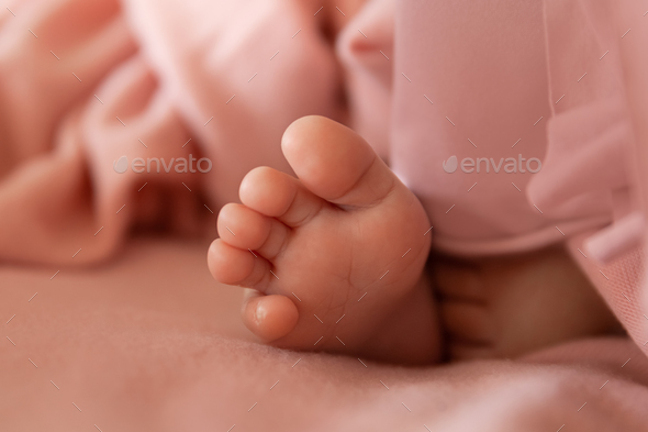 Newborn baby foot on soft wrap as a background in light peach or pink tone, tiny toes of infant - Stock Photo - Images
