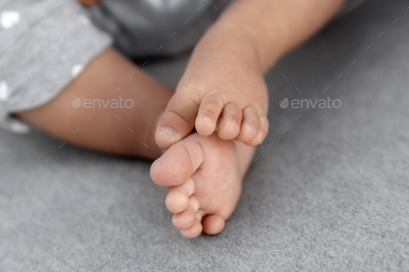 Closeup of infant baby feet on grey blanket as a background, babyhood and childhood concept - Stock Photo - Images