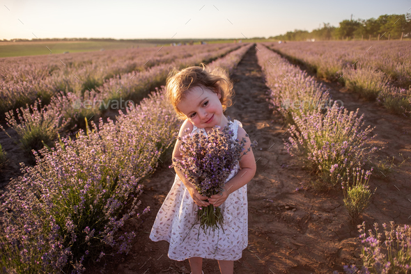 Close-up portrait of little girl in flower dress holding bouquet with ...