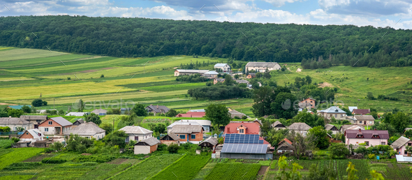 Top view of solar panels in yard, houses, gardens and estates and nature landscape on horizon