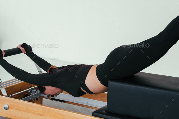 Woman doing Pilates on reformer bed. Pilates reformer, girl doing ...