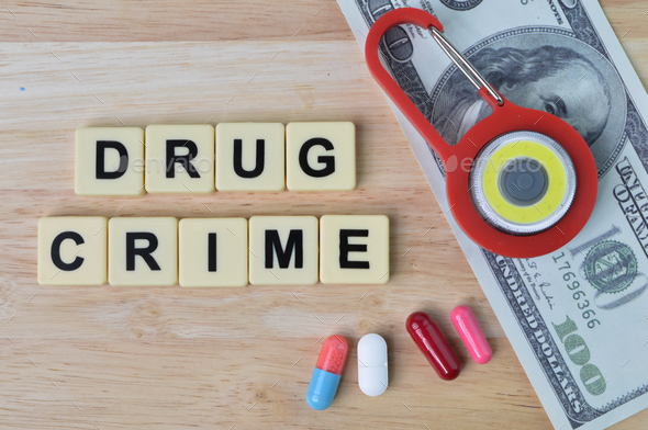Toy padlock, pill capsules, money banknote and square letters with text DRUG CRIME.