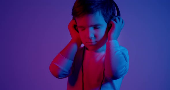 Child Listening to Music With Headphones Over Neon Lights