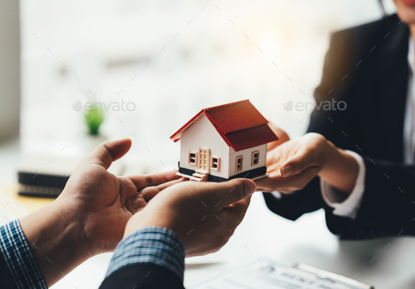 Real Estate Broker Or businessman holding white house model in hand.Mortgage loan approval home loan