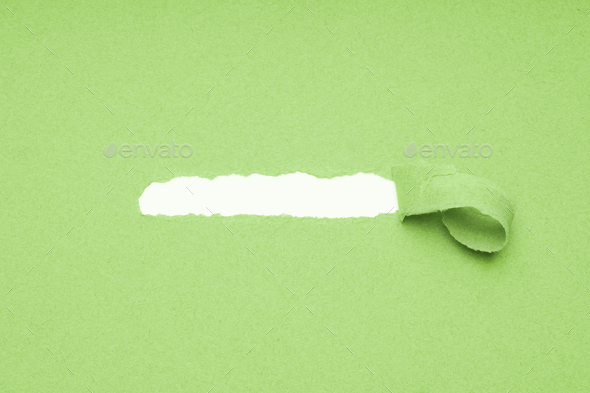 hole torn in green paper background to reveal hidden copy space