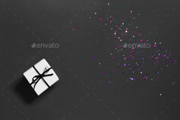 Festive black background with sparkles and a small white gift box.