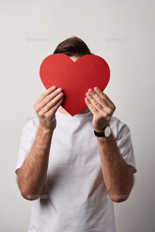 man with obscure face holding empty red paper cut heart card