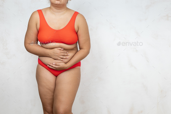 Naked overweight woman bending over touch stomach, white background. Woman  in red underwear with Stock Photo by burmistrovaiuliia