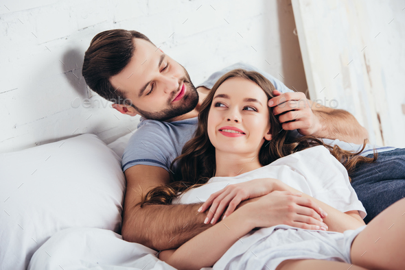 adult loving couple gentle hugging in bedroom while man touching hair ...