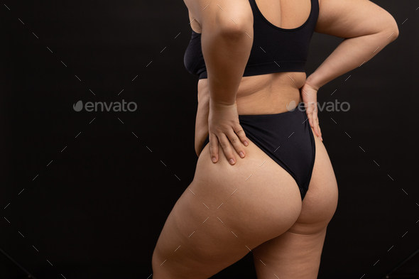 Overweight woman in black underwear pull up panties, back view. Flaunt  figure imperfections Stock Photo by burmistrovaiuliia