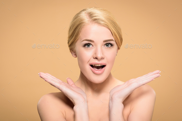 surprised young naked woman smiling at camera isolated on beige Stock