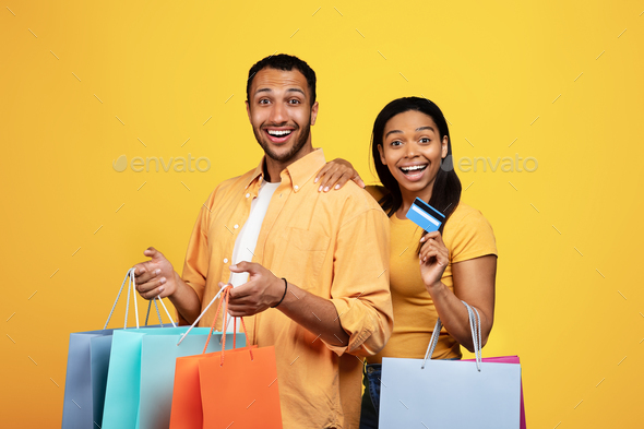 Glad surprised millennial african american male and female hold many packages, recommend credit card