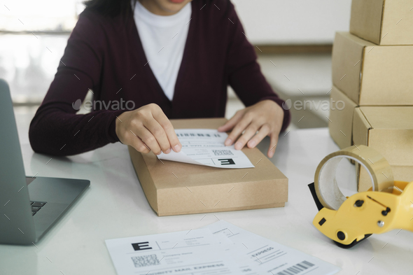 Young business owner putting shipping label on parcel.