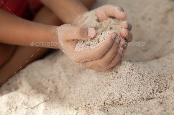 Boy holding sand in hands at the beach in summer time, family vacation concept - Stock Photo - Images