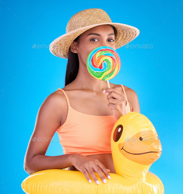 Portrait, lollipop and rubber duck with a woman on a blue background in  studio ready for summer swi Stock Photo by YuriArcursPeopleimages