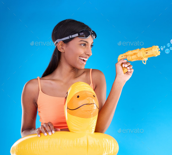 Bubbles, summer swimsuit and woman with bubble gun in a studio with fun and happiness. Isolated, bl