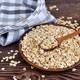 Oat flakes uncooked in wooden bowl with spoon on a dark wooden table. Concept of healthy eating - PhotoDune Item for Sale