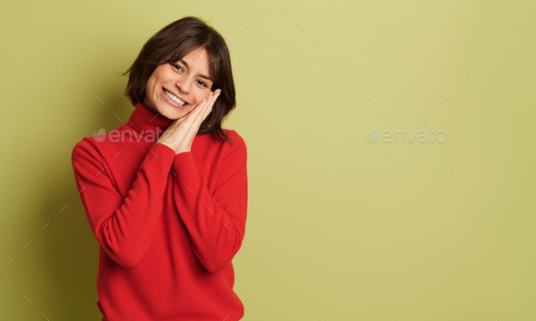Smiling woman blushing in red turtleneck against studio background