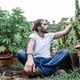 young caucasian man sitting on the ground in a large garden among the pots of marijuana plants - PhotoDune Item for Sale