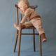  Portrait Cute one year old baby girl, wearing brown suit, sitting on a wooden chair. - PhotoDune Item for Sale