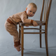 The kid hangs on a wooden chair, trying to climb on it - PhotoDune Item for Sale