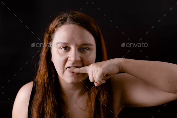 Upset young woman biting finger. Self harm, pain, suffering. Restless unhappy girl. Mentally