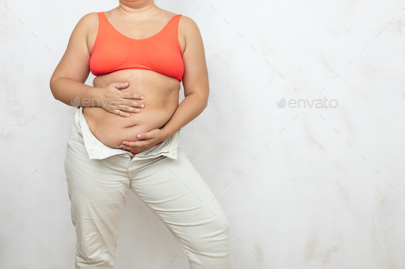Hands of overweight woman massage hanging folds on belly, white background.  Woman in red underwear Stock Photo by burmistrovaiuliia
