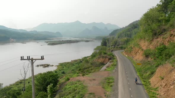 Aerial view of Motorcyclist on road next to Mekong River, Laos  alt