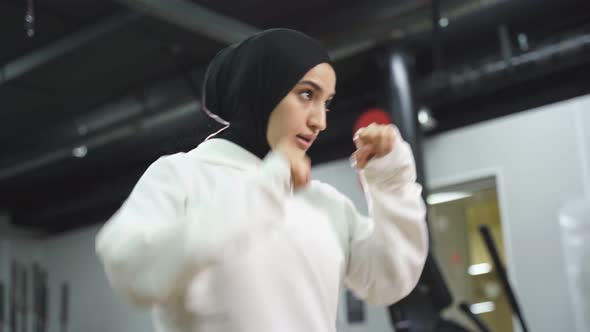 Muslim Female Boxer in a Sports Hijab is Engaged in Boxing an Arab Woman is Doing Exercises
