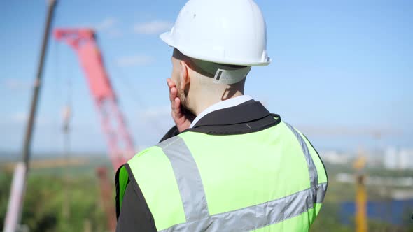 Back View Thoughtful Caucasian Foreman Standing at Industrial Park with Tower Crane Looking Away alt
