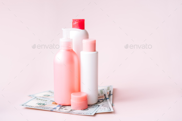 Tubes with hygiene products on dollar bills against pink background