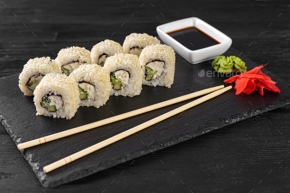 Sushi roll Philadelphia with salmon, sesame seeds, avocado, cream cheese on black slate background