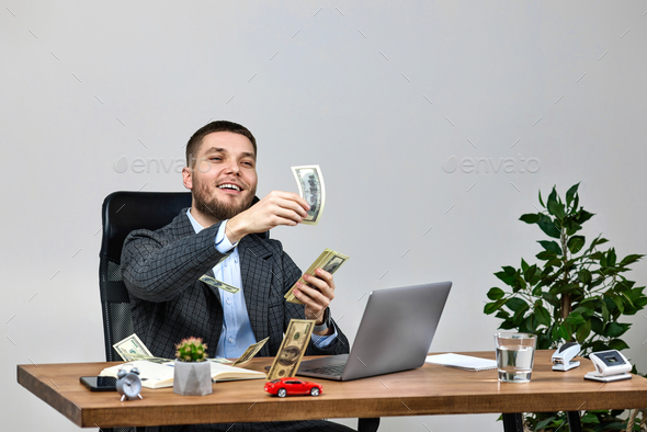 young bearded businessman working on laptop and throwing money