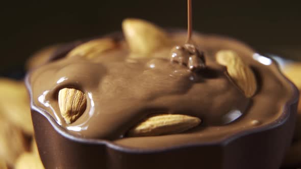 Pouring Hot Melted Chocolate and Almond Nuts Texture Close Up