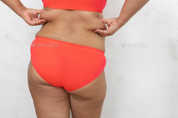 Rearview of unrecognizable adipose, fat, big obese woman in red lingerie  hold sagging friable flabs Stock Photo by burmistrovaiuliia