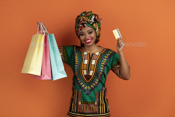 Happy black lady showing colorful shopping bags and bank card