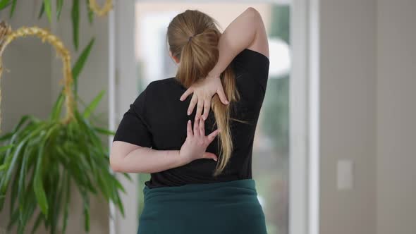 Back View of Persistent Overweight Young Woman Training Reaching Hands Behind Back alt