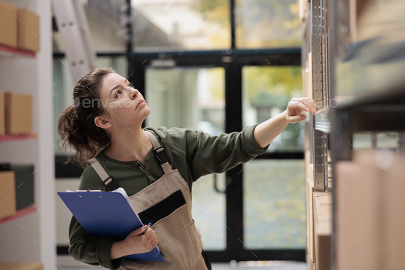 Stockroom worker looking at shelves full with carton boxes Stock Photo