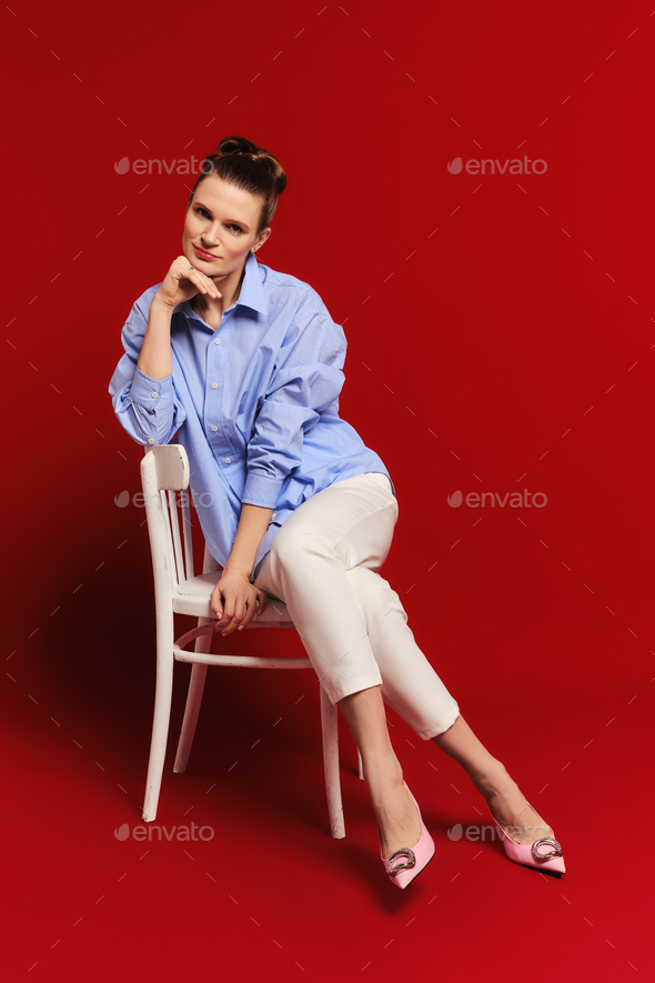 Adult woman sits on chair and looks straight forward