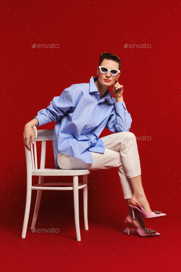 Adult woman sits in profile on chair and looks straight forward