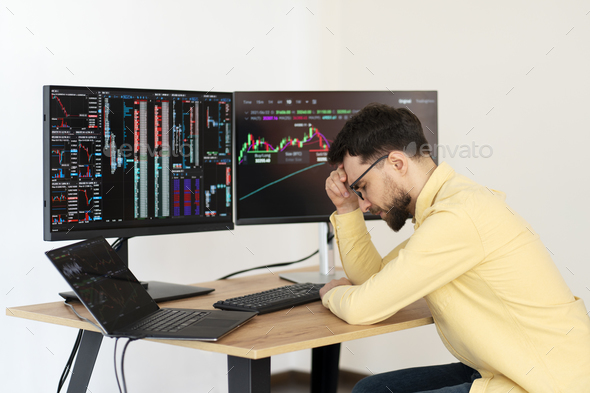 Overworked bearded man, crypto trader having headache, lost money sitting in office