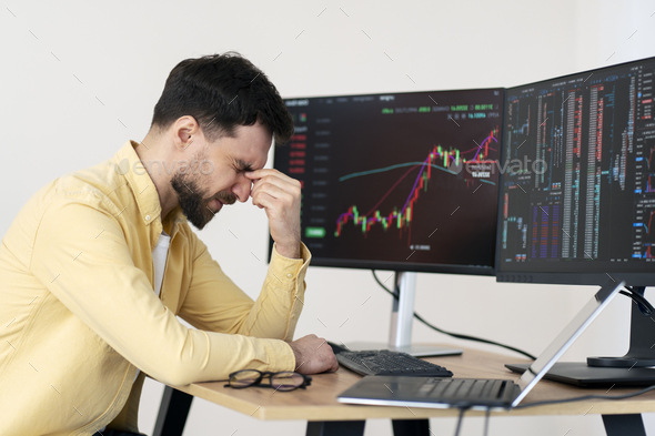 Tired man, crypto trader having headache, lost money sitting in office. Failure business, bankruptcy
