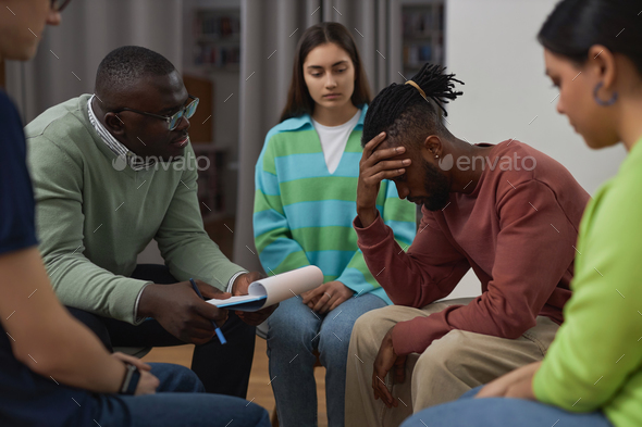 Young black man crying in support group circle