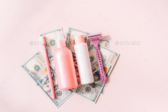 Women\'s personal care products on dollar bills against pink background