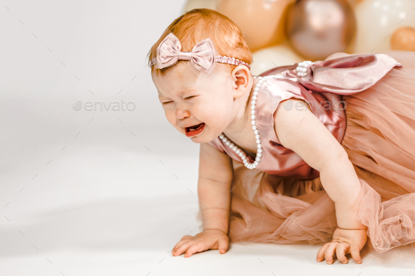 Little crying unhappy redhead baby girl celebrates first birthday anniversary. 1 year family party