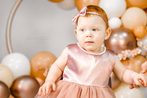 Little redhead baby girl celebrates first birthday anniversary. 1 year family baloons party.