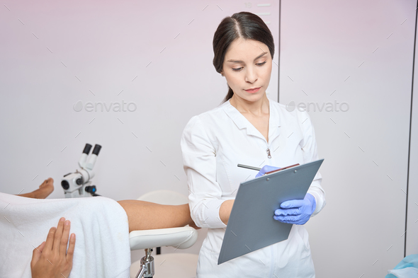 Woman gynecologist is writing down the complaints of the patient